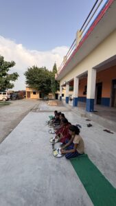 Bal Bhojan Seva Trust distributing nutritious meals to school children in the presence of the school principal.
