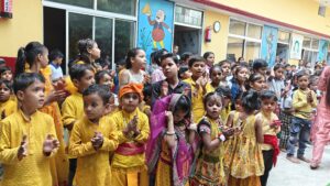 Children coming together to celebrate Janmashtami in a joyful and festive atmosphere, sharing smiles and enjoying the special occasion with their friends and teachers.